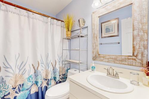 a bathroom with a sink and a toilet and a shower curtain at Sunset Terrace in Avon
