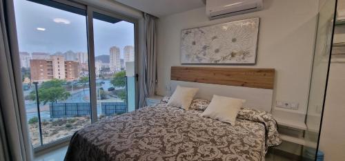um quarto com uma cama e uma grande janela em APARTAMENTOS OASIS DE LA CALA em Finestrat