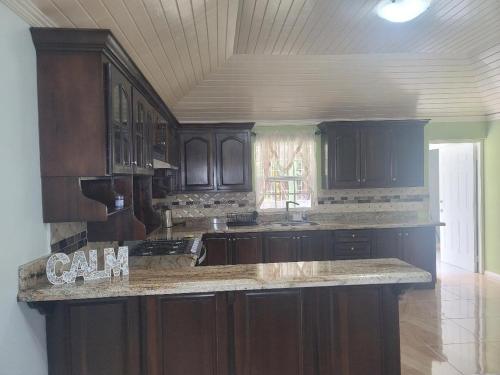 cocina con armarios de madera y encimera de granito en Casa Serenity, en Priory