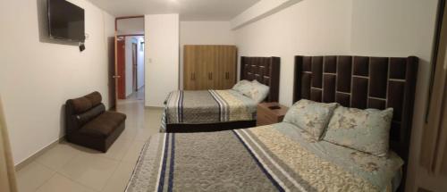 een hotelkamer met 2 bedden en een stoel bij Pacheco APARTMENT in Cuzco