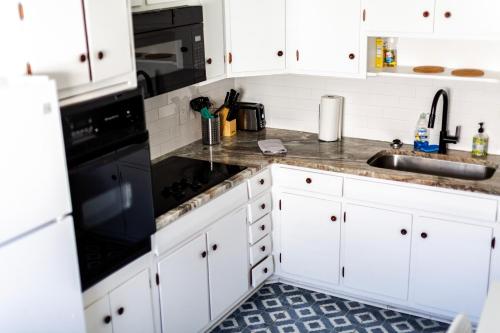 a kitchen with white cabinets and black appliances at Fantastic 3BR Close to Botanical Gardens and Airport in Norfolk