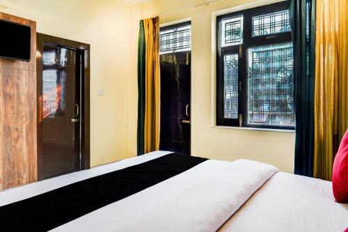um quarto com uma cama e duas janelas em Capital O 66972 Sangam Hotel And Resort em Kotdwāra