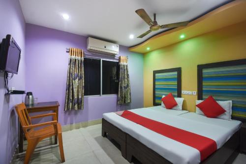 a bedroom with a bed and a tv and a chair at Hotel Kohinoor in Durgāpur