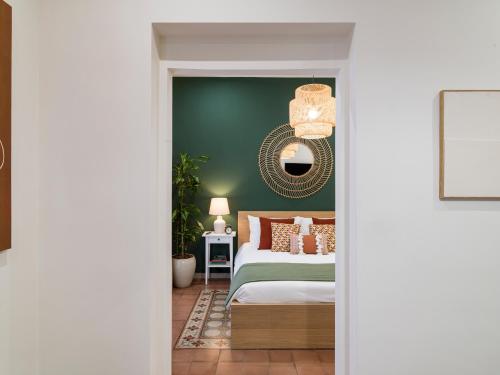 ein Schlafzimmer mit einer grünen Wand, einem Bett und einem Spiegel in der Unterkunft Kondo Maisons in Catania