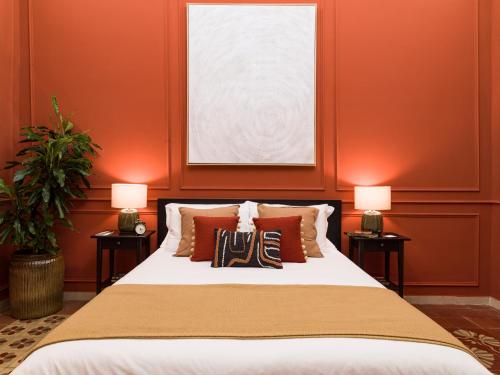 a bedroom with orange walls and a bed with two lamps at Kondo Maisons in Catania