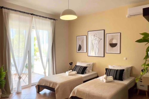 two beds in a room with a window at Villa Oinoni in Egina