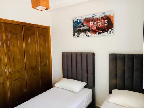 1 dormitorio con 2 camas y un cartel en la pared en Fantastique Appartement avec piscine sur la plage M2 en Tánger