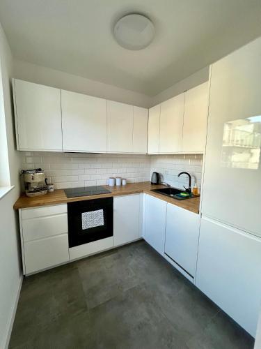 an empty kitchen with white cabinets and a sink at Apartament Studio Centrum in Koszalin