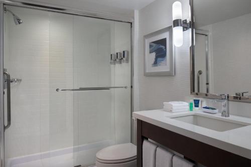 a bathroom with a shower and a toilet and a sink at Four Points by Sheraton Hotel & Conference Centre Gatineau-Ottawa in Gatineau