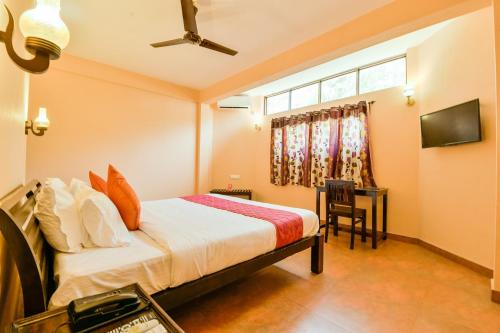 Schlafzimmer mit einem Bett, einem Schreibtisch und einem Fenster in der Unterkunft OYO 13415 Cherai Village Home Stay in Cherai Beach