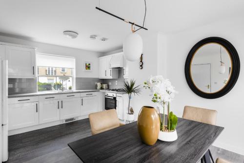a kitchen with white cabinets and a table with a mirror at Luxurious 3 Bed House with Free Parking in Braintree, Close to the Train Station & City Centre in Braintree
