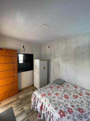 a bedroom with a bed and a refrigerator in it at Espaço de lazer 3E in Dourados