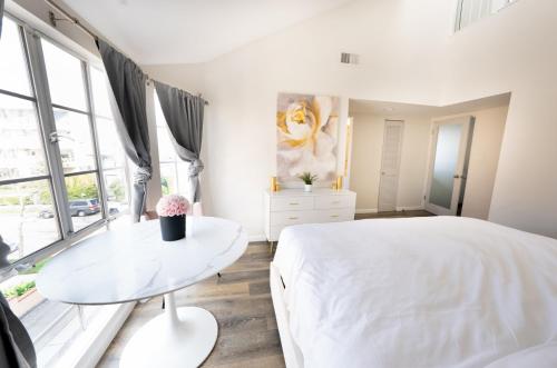 a white bedroom with a white bed and a table at Beautiful Beverly Hills Townhome in Los Angeles