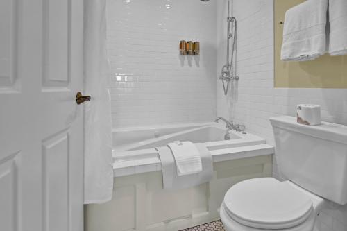 a white bathroom with a toilet and a bath tub at St James Hotel in Red Wing