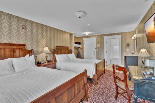 a bedroom with two beds and a desk with a chair at St James Hotel in Red Wing
