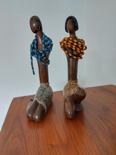 two small wooden figurines sitting on a wooden table at See to Sea in Ericeira