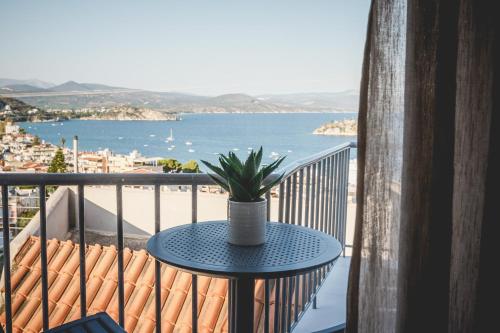 een tafel met een plant op een balkon met uitzicht op de oceaan bij Votsalo Tolo in Tolo