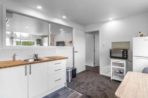 a kitchen with white cabinets and a sink and a refrigerator at Nine Acres in Invercargill