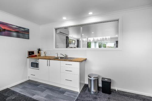 a white kitchen with a sink and a window at Nine Acres in Invercargill