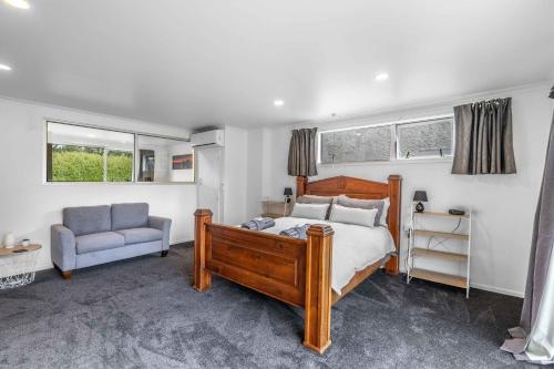 a bedroom with a bed and a chair and windows at Nine Acres in Invercargill