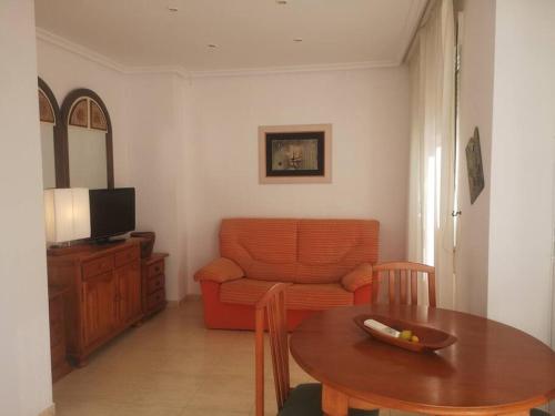 uma sala de estar com um sofá laranja e uma mesa em Torremar vera playa naturista em Vera