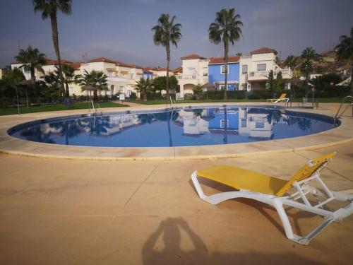 uma cadeira amarela sentada em frente a uma piscina em Torremar vera playa naturista em Vera