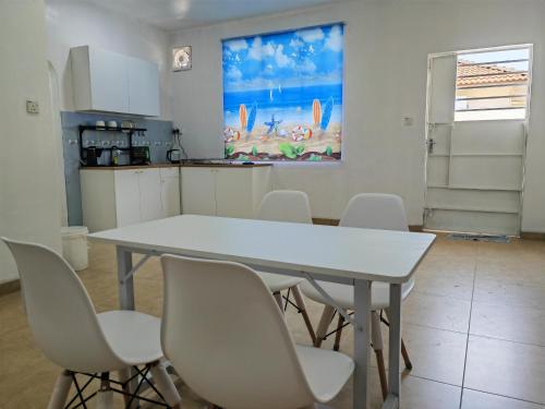 a kitchen with a white table and white chairs at Cozy Roomstay Padang Serai in Padang Serai