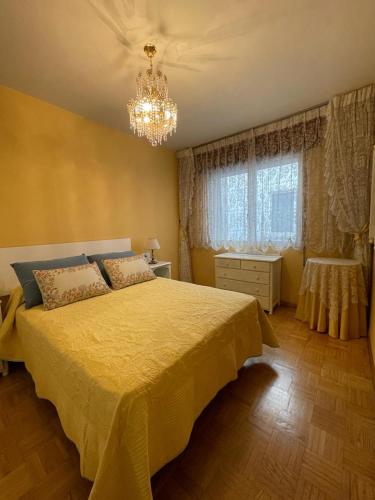 a bedroom with a yellow bed and a chandelier at Apartamento Curros Enríquez in Cambados