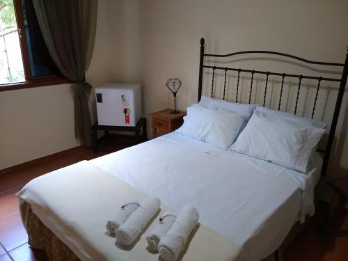 Un dormitorio con una cama blanca con toallas. en Pousada Castelinho Conservatória, en Conservatória