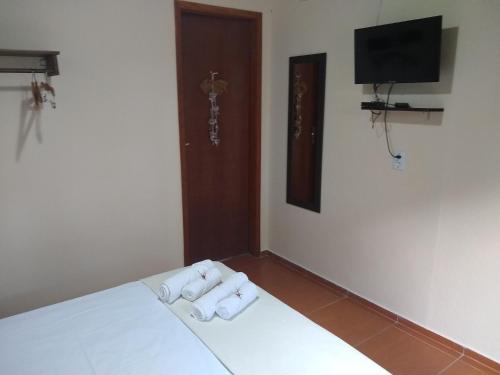 a bedroom with two towels on a bed with a television at Pousada Castelinho Conservatória in Conservatória