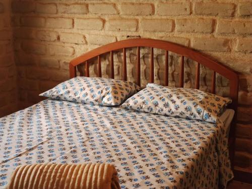 a bed with two pillows on it with a brick wall at Casa Jasmim in Cavalcante