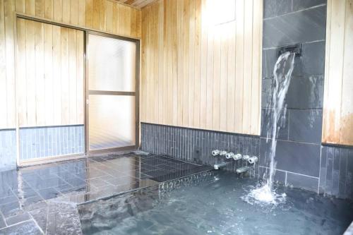 La salle de bains est pourvue d'une baignoire avec une fontaine à eau. dans l'établissement ～みらい荘～　天然温泉付き一日一組様限定の６４坪広々民泊別荘, à Kirishima