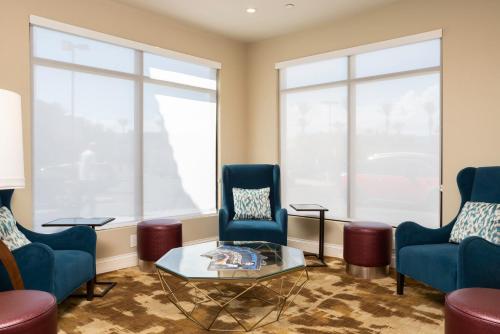 a living room with two blue chairs and a glass table at Hilton Garden Inn Phoenix Airport in Phoenix