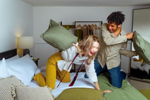 a man and a woman jumping on a bed at Kondo Maisons in Catania
