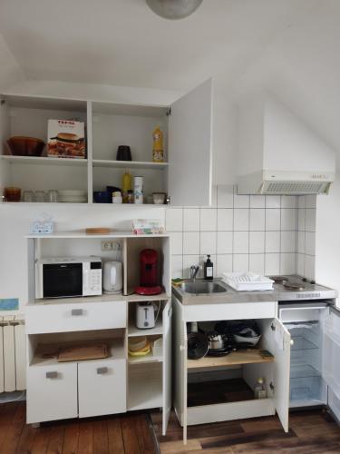 een keuken met witte kasten en een wastafel bij Le Faubourg in Saint-Quentin
