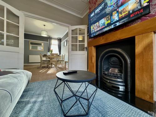 a living room with a table and a fireplace with a tv at Freeston House - Great for Contractors or Family Holidays in Cleethorpes