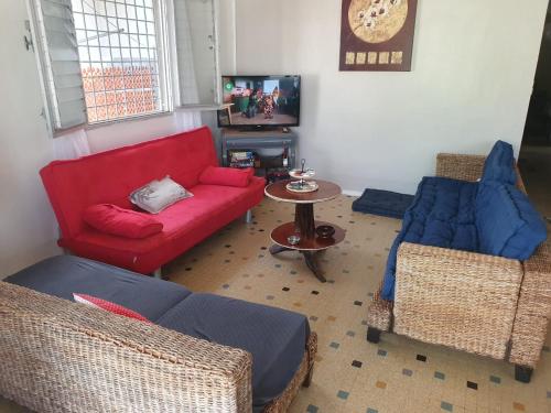 Una sala de estar con un sofá rojo y dos sillas. en Maison YZIDEE, en Fort-de-France