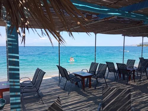a patio with chairs and a table on the beach at Akri Rooms in Akrata