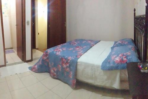 a bedroom with a bed with a blue and red blanket at Hospedaria Meu Lar in Rio das Ostras