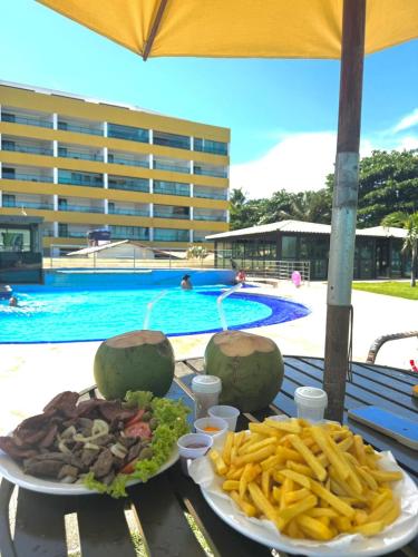 a table with two plates of food and french fries at Flat Tabatinga Nord, vista para o mar in Conde