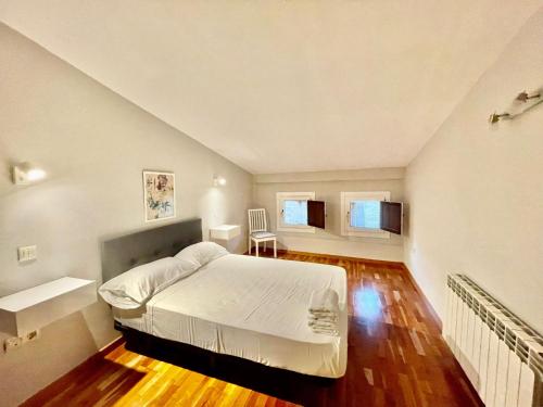 1 dormitorio con cama blanca y suelo de madera en Barco, en Toledo