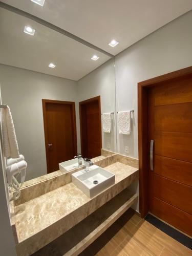 baño con 2 lavabos y espejo grande en Apartamento Avenida, en Camanducaia