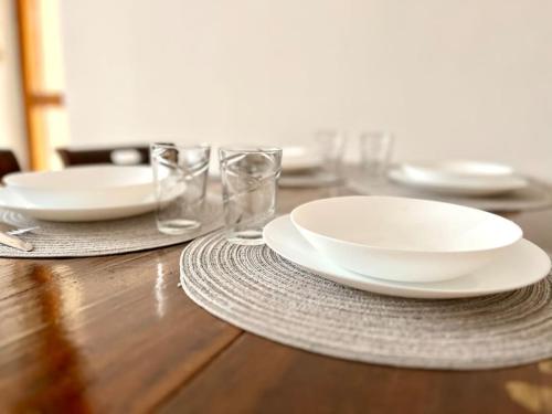 a wooden table with white plates and glasses on it at Casa Marconi - City Center in Bra