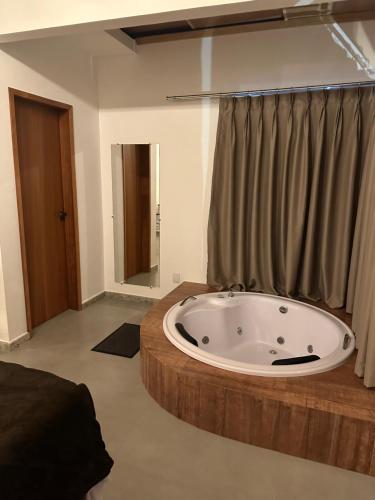 ein Bad mit einer großen Badewanne in einem Zimmer in der Unterkunft CORAÇÃO DO ALTO CHALES in Caparaó Velho
