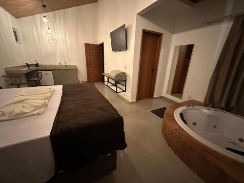 a bedroom with a large bed and a bath tub at CORAÇÃO DO ALTO CHALES in Caparaó Velho