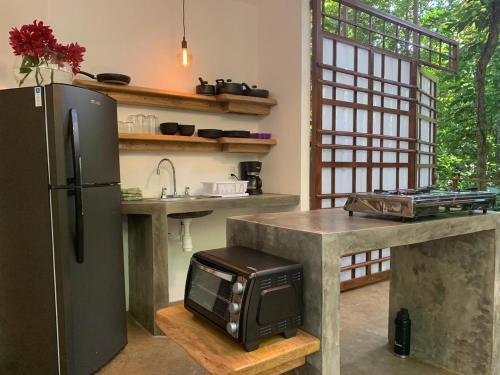 a kitchen with a refrigerator and a counter with a microwave at Peaceful Jungle Villa Kona - Pool & Parking for 2 persons in Puerto Viejo