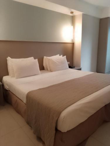 een slaapkamer met een groot bed met witte kussens bij El Mistic hotel in Rio de Janeiro