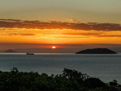 a sunset over the ocean with a boat in the water at Bangalô Ilhabela in Ilhabela