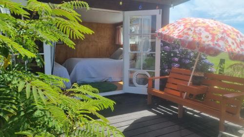 a porch with a bench and an umbrella at Delightful 1 bedroom tiny house, with retro Poptop in Westport