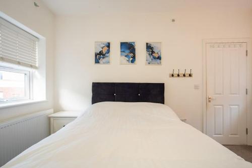 een wit bed in een slaapkamer met twee foto's aan de muur bij Watford Central Serviced Apartments 2 in Watford